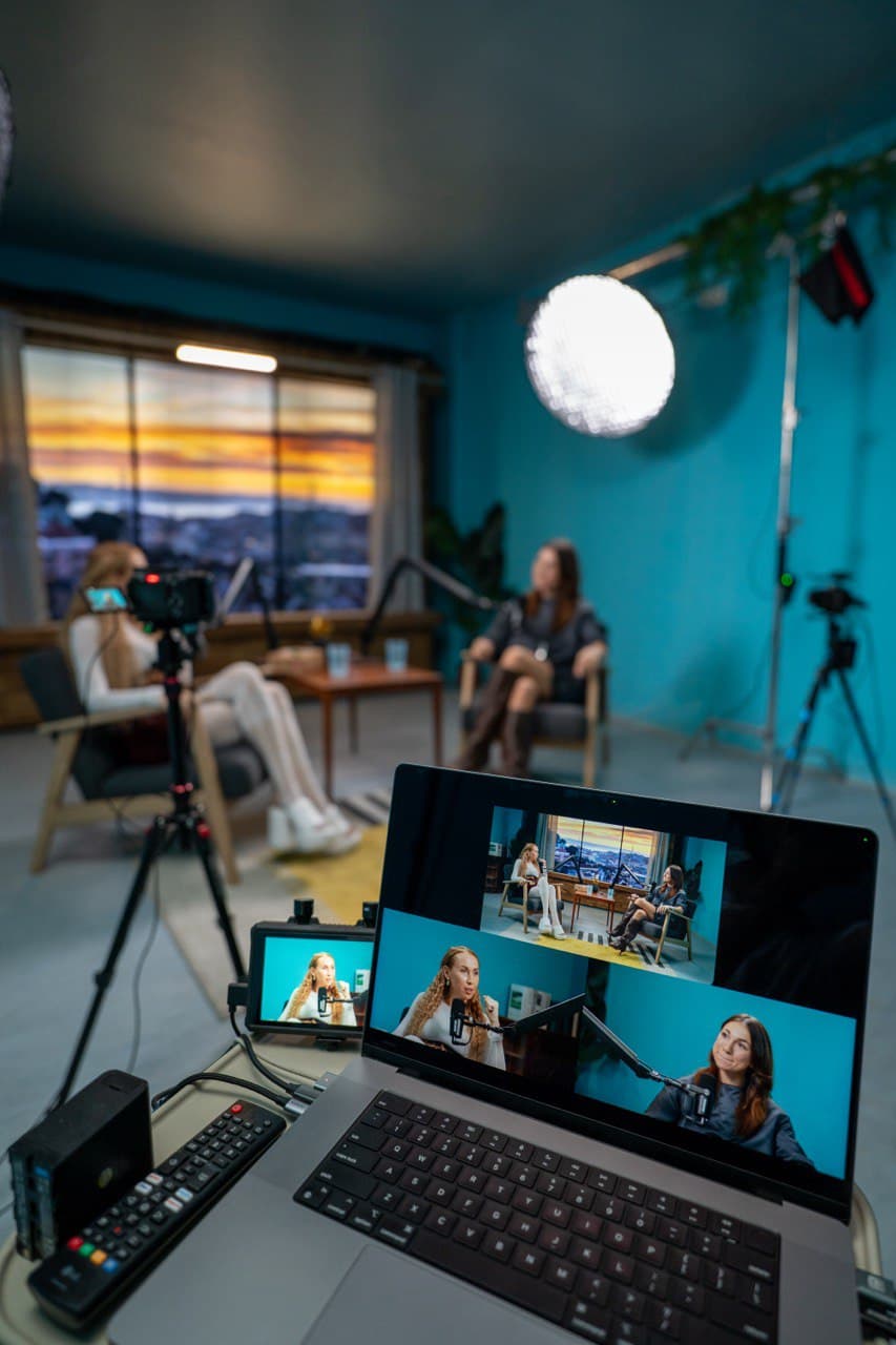 Behind the scenes - Multi-camera podcast production setup with laptop monitoring and sunset skyline backdrop